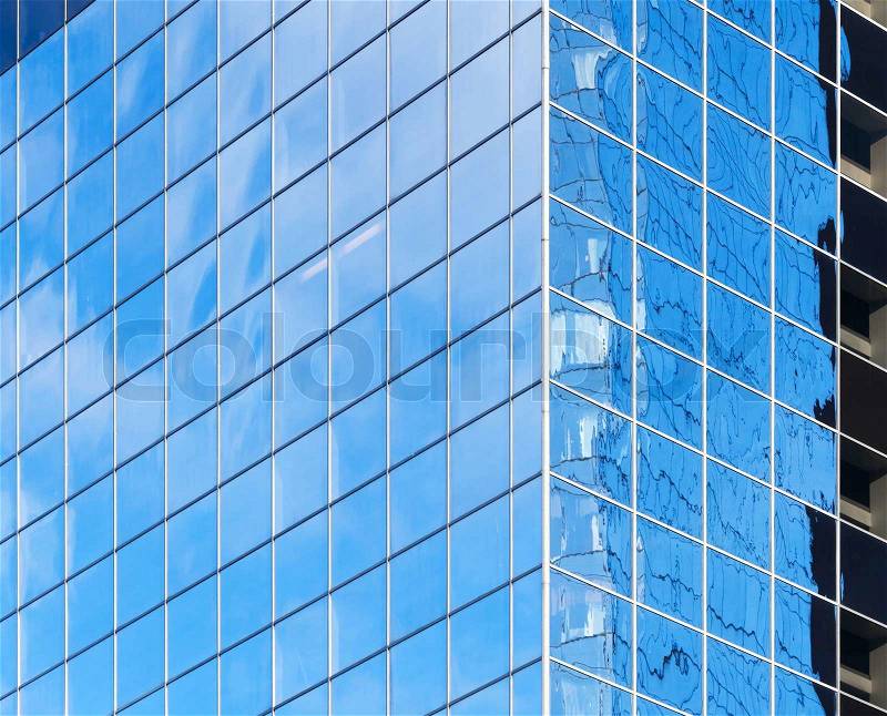 Corner of modern office building with bright blue sky reflections in windows, stock photo