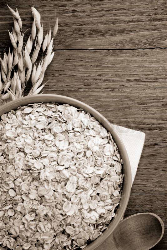 Oat flakes in bowl on wood, stock photo