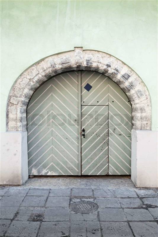 Ancient green wooden gate with arch in old building facade. Tallinn, Estonia, stock photo