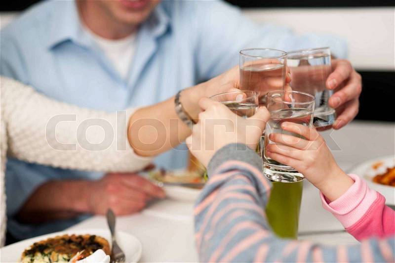 Family toasting water glasses in celebration, stock photo