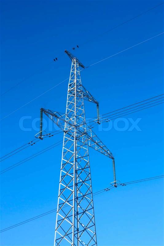 Electrical high-voltage metal pillar against the background of blue cloudless sky, stock photo
