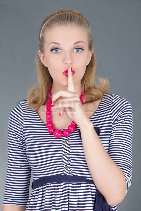 Attractive pinup girl in striped dress with finger on lips, stock photo