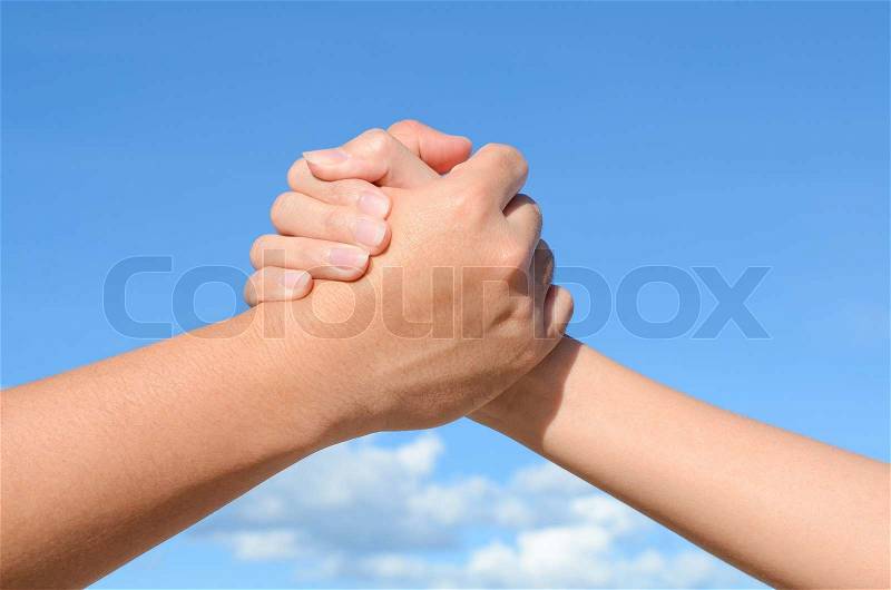 Partner hand between a man and a woman on blue sky background, Teamwork, stock photo