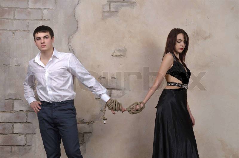 Image of a male and female model in a studio, their hands tied with a rope, stock photo