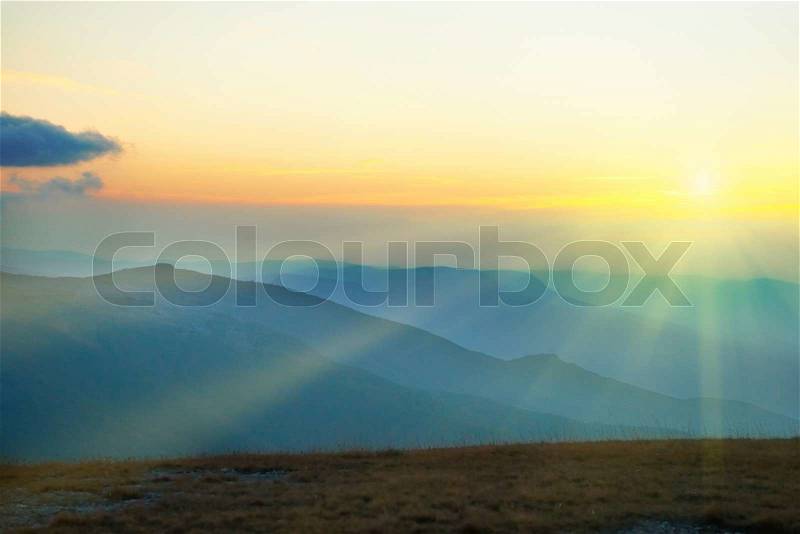 Beautiful sunset at the mountains. Colorful landscape with sun and blue sky, stock photo