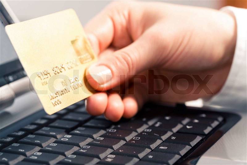 Photo of human hand holding the credit cart over black keyboard, stock photo