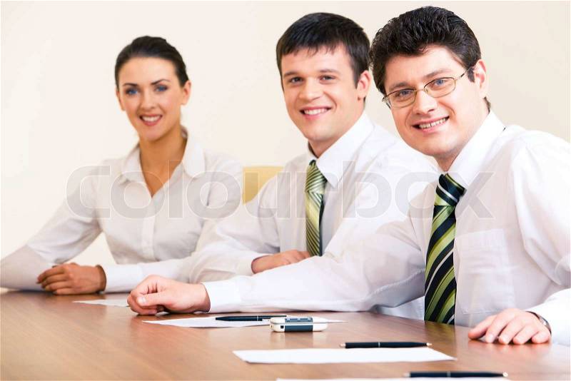 Portrait of confident business people sitting at the table and looking at camera with their boss at the front, stock photo