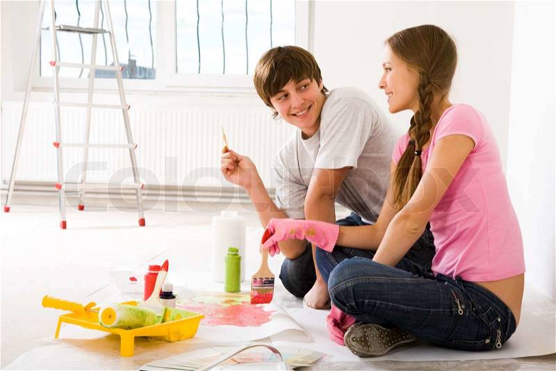 Photo of young couple sitting on floor of new flat and interacting, stock photo