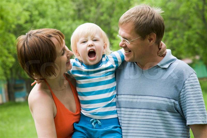 Photo of parents holding son screaming on camera, stock photo