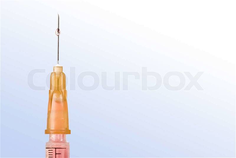 Macro image of syringe needle with drop of vaccination over blue background, stock photo