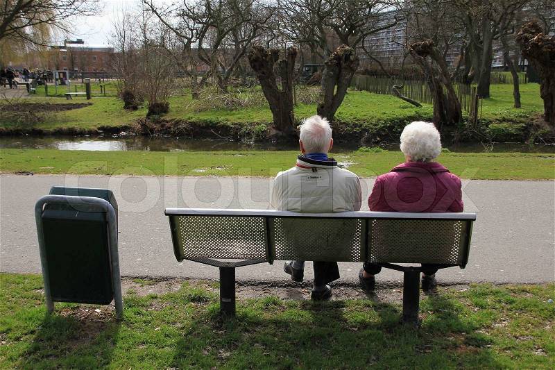Retired senior couple sitting on the bench have a break and have a wonderful view in park in spring, stock photo