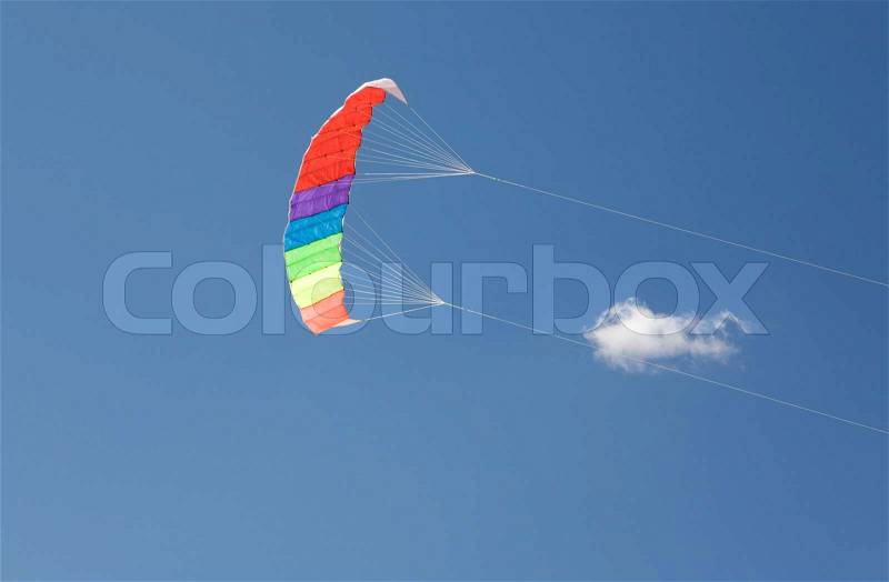 Image of colorful kite flying into bright blue sky with tiny cloud on background, stock photo