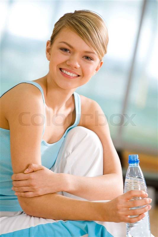 Portrait of lovely girl holding bottle of water in hand and smiling, stock photo
