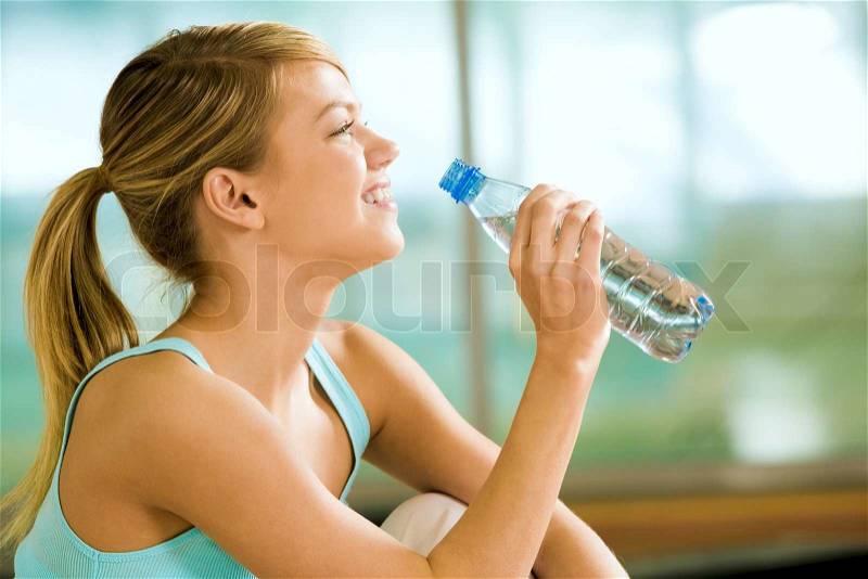 Profile of beautiful woman going to drink some water fron plastic bottle after workout, stock photo