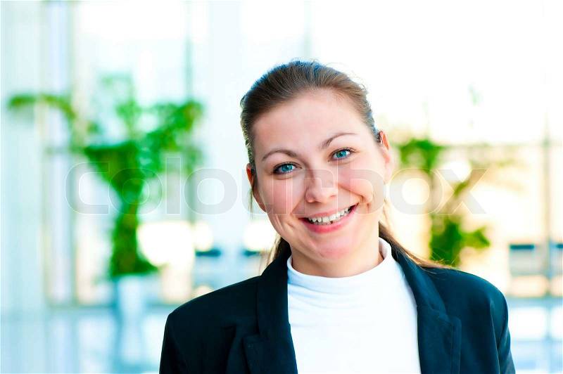 Portrait of a smiling girl on the background of the manager de-focus office interior, stock photo