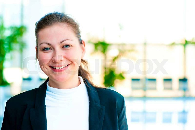 Portrait of a smiling girl on the background of the manager de-focus office interior, stock photo