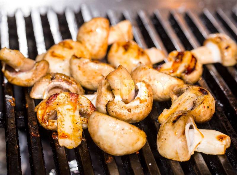 Cooking mushrooms on the grill in the restaurant, stock photo