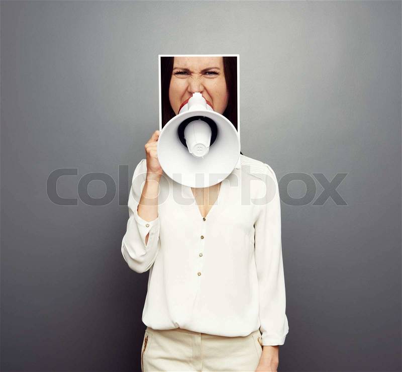 Concept photo of young female screaming in megaphone over dark background, stock photo