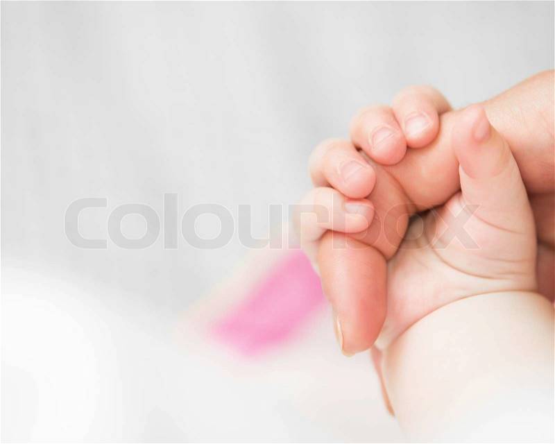 Close-up of baby\'s hand holding mother\'s finger, stock photo