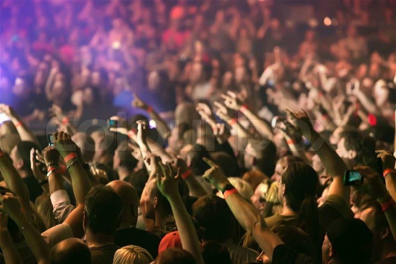Crowd cheering and hands raised at a live music concert, stock photo