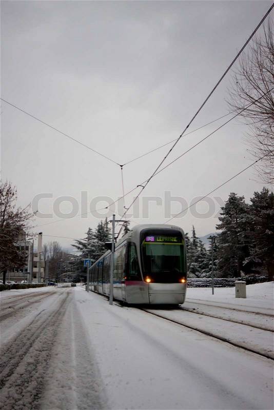 Tram with snow covered rails in the Grenoble City, France, stock photo