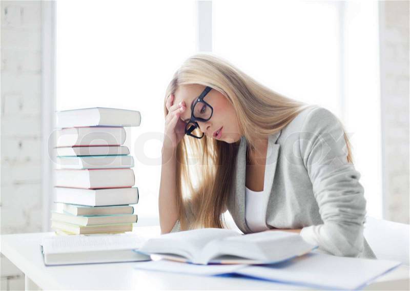Student with pile of books and notes studying indoors, stock photo