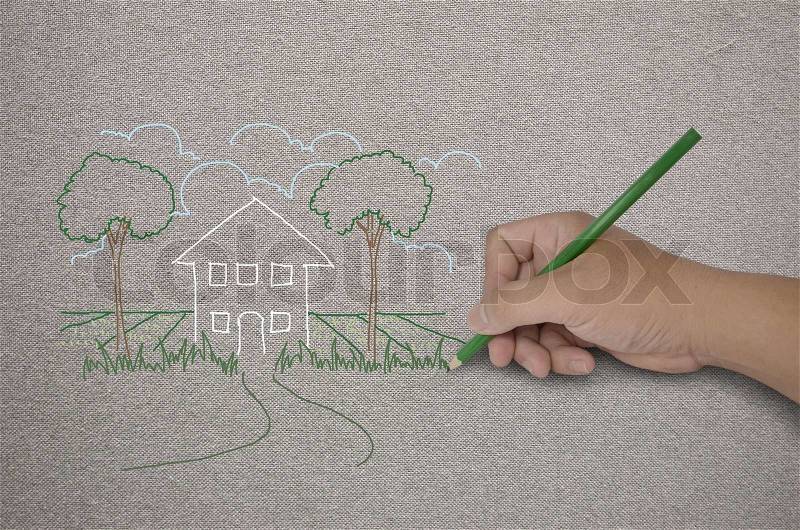 Hand drawing a house with green pencil on fabric, stock photo