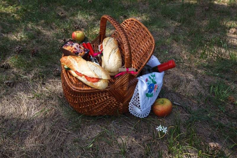 Picnic Time. Picnic basket with food, fruits and bottle of wine, stock photo