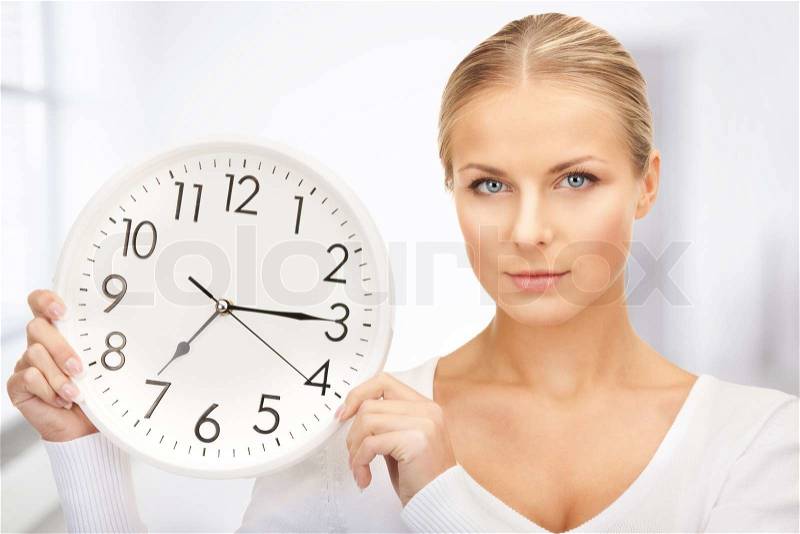 Picture of woman holding big clock in office, stock photo
