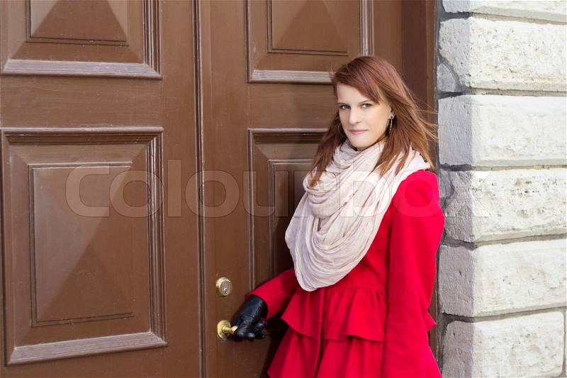 Young beautiful redhaired woman in front of the old door, stock photo