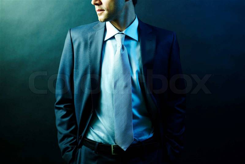 Figure of elegant businessman in suit posing in darkness, stock photo