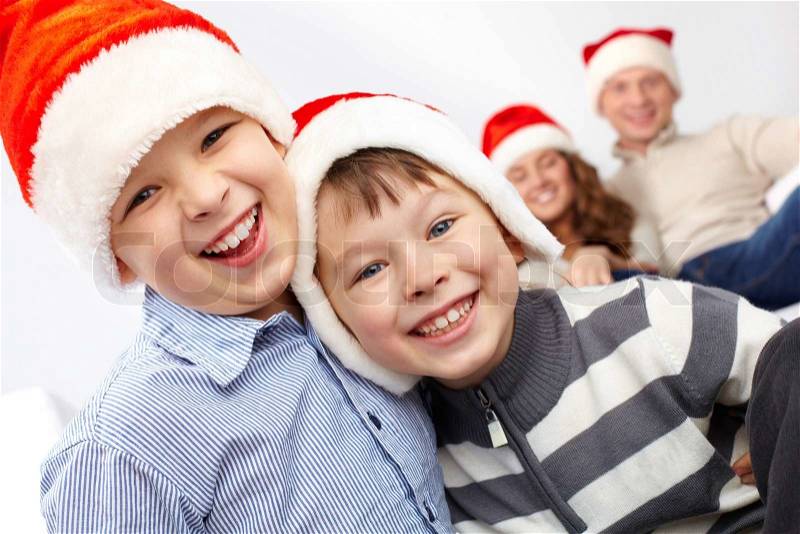 Two lads in Santa hats laughing and looking at camera, stock photo