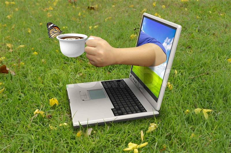 Hand holds a cup of coffee out of laptop screen, stock photo