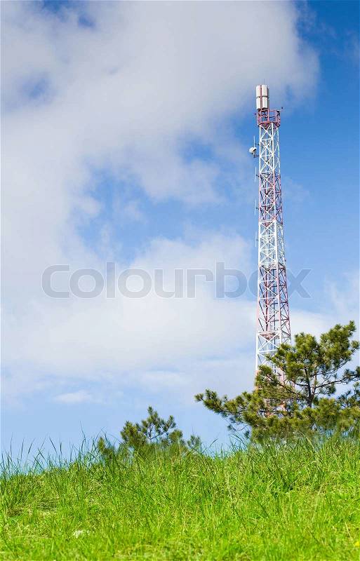 Green field and radio tower against the background cloudy sky, stock photo
