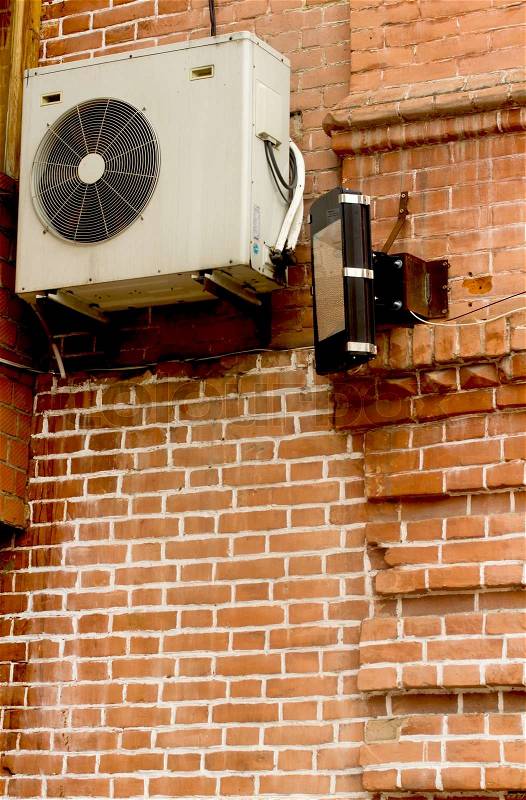 Air conditioning heat pump mounted on old brick wall, stock photo