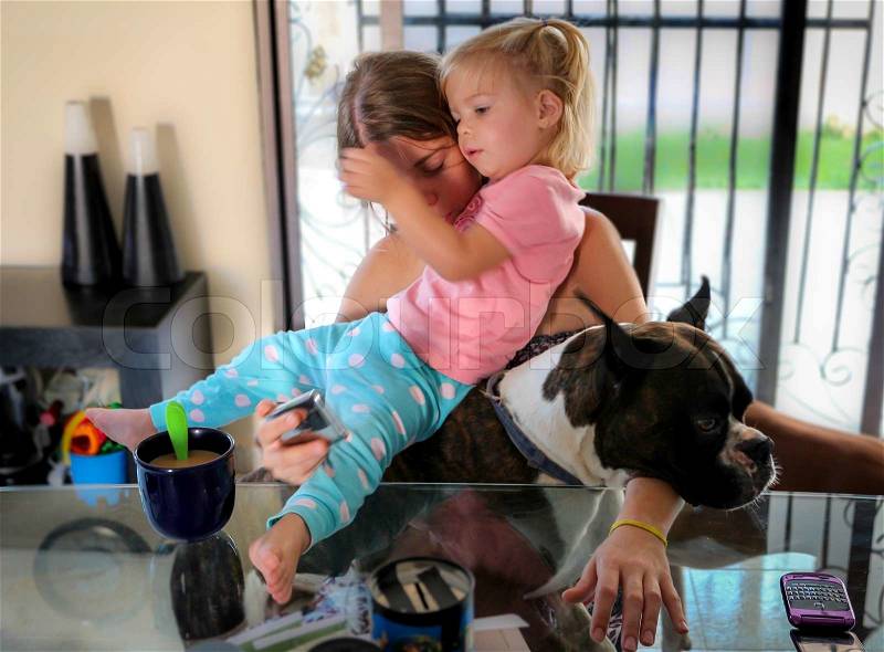 Monday morning Chaos: holding a child and a dog while trying to answer the phone and serve breakfast, stock photo