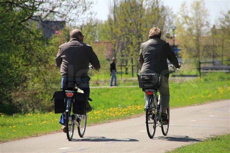 Walking man, a retired couple are biking, having fun in their spare time in the open air in spring, stock photo