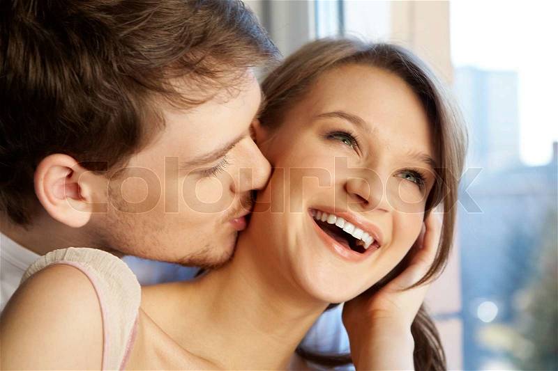 Close-up of young man kissing happy woman , stock photo