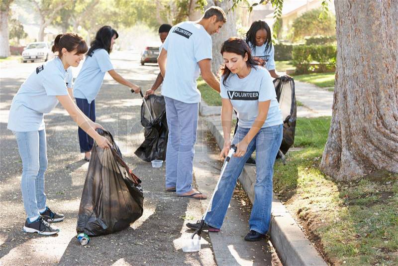 Team Of Volunteers Picking Up Litter In Suburban Street, stock photo