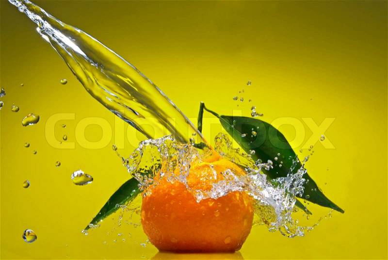 Tangerine with green leaves and water splash on green background, stock photo