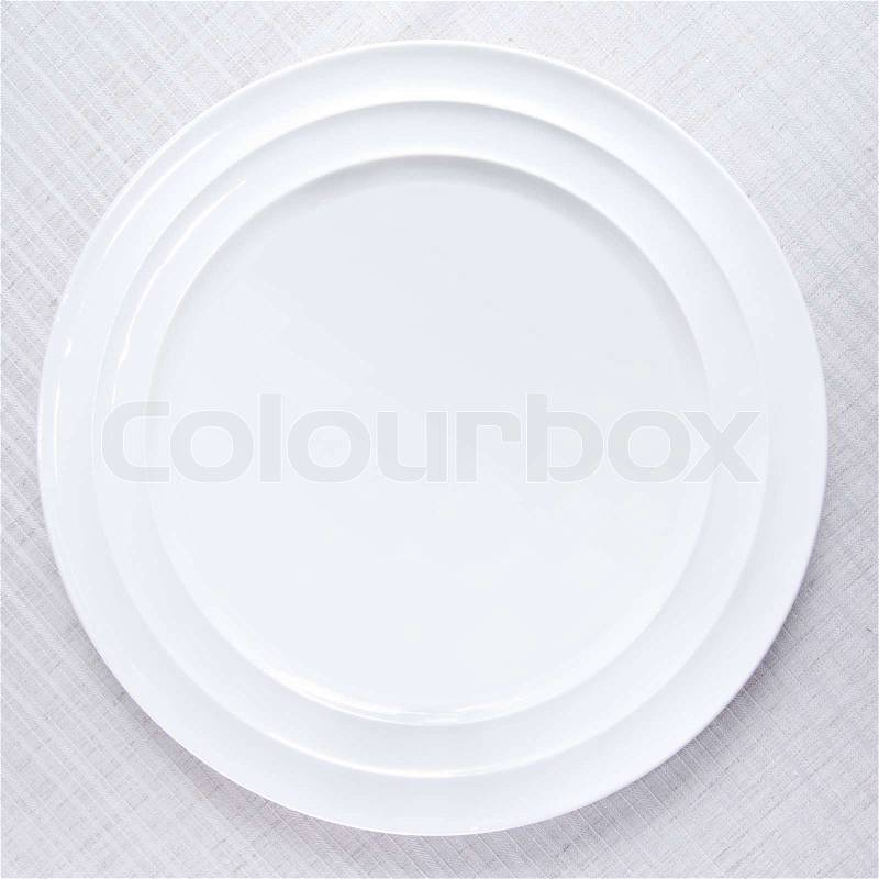 Empty white plate on tablecloth, stock photo