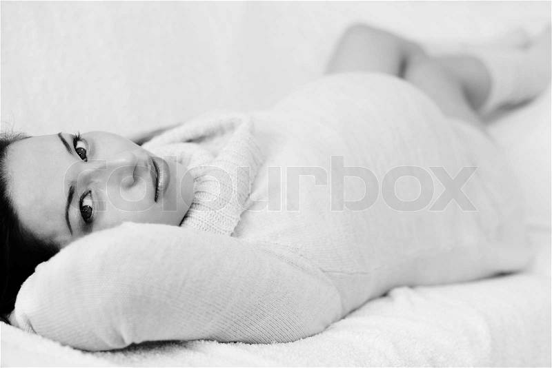 Pretty pregnant woman laying on the sofa in black and white, stock photo