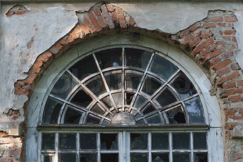 Fragment of the old round window with broken windows, stock photo