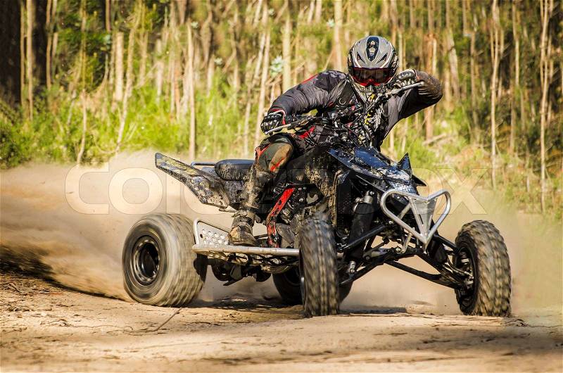 ATV racer takes a turn during a race on a dusty terrain, stock photo