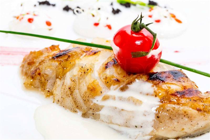 Roasted fillet of grilled fish in a white sauce, stock photo