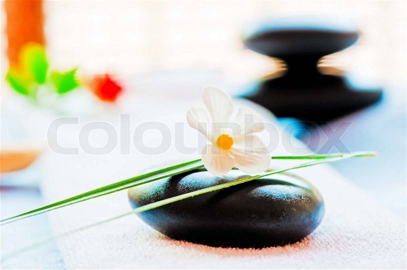 Still life with a black stone and a flower in the style of zen-like, stock photo