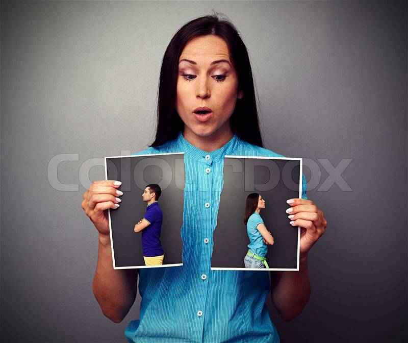 Amazed woman looking at disrupt photo of couple in quarrel, stock photo
