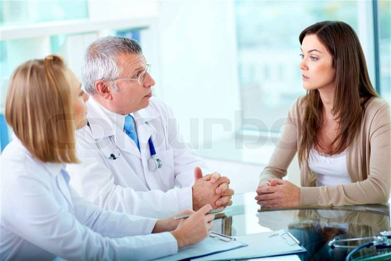 Portrait of confident practitioners consulting patient in hospital, stock photo