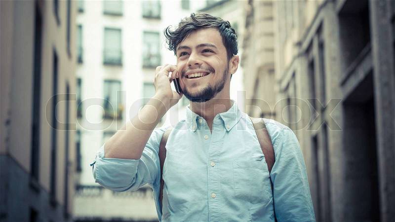 Stylish man in the street at the phone in the city, stock photo