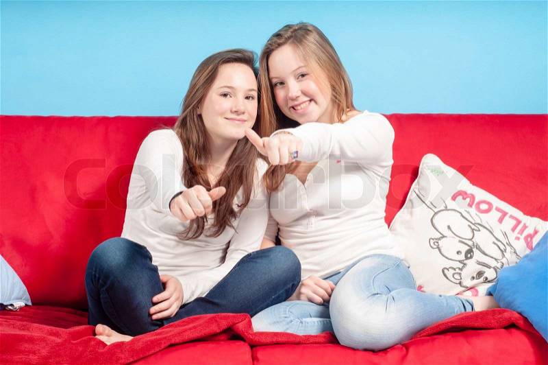Sisters playing nose to nose on the couch in the living room, stock photo